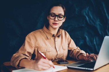 Dalgın akıllı hipster blogger bazı fikir dizüstü bilgisayar üzerinde kendi web sayfası geliştirmek için Not Defteri'nde belirterek bağlı kablosuz 4 g için Internet. Bilgi Web sitesinden yeniden öğrenci konsantre