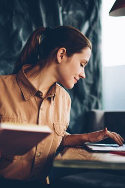 Dalgın yetenekli beyaz öğrenci dizüstü bilgisayar Projesi'nde eğitim üzerinde çalışmak için kablosuz 4 g bağlıyken ders kitabı elinde tutan Internet. Bilgi web sitelerinde arama akıllı hippi kız