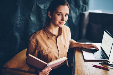 Yarım dijital bilgisayar seminerde hazırlama büyüleyici yetenekli öğrenci portresi alan coworking içinde kablosuz internet bağlı. El kameraya bakarak ders kitabı ile çekici hippi kız