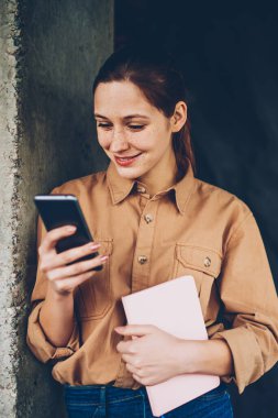 Smartphone aygıt profili güncelleştirmek için 4 g bağlıyken neşeli hipster blogger gülüyor Internet. Pozitif öğrenci ders kitabı elinde telefon sosyal ağlarda komik Haberler okuma ile