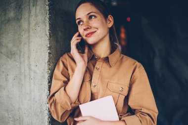 Smartphone üzerinde arama ve işleç ile konuşmak için telefon hattında bekliyor elinde ders kitabı ile şirin hippi kız. Boş zamanlarında üzerinde modern hücresel iletişim oldukça olumlu genç kadın