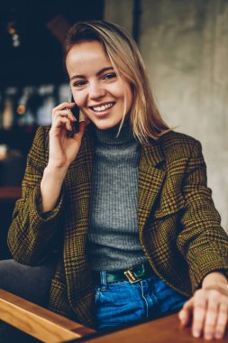 Başarılı genç işkadını yarım uzunluk portre smartphone aygıtında arkadaşıyla konuşurken kameraya gülümseyen şık kıyafeti giymiş. Neşeli hipster blogger cep üzerinde arama