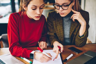 Kırpılmış görüntü iki yetenekli kadın tasarımcılar tasarım kroki üzerinde ortak çalışma. Ciddi öğretmen öğrenci özel ders masaüstü dizüstü bilgisayarlar ile oturma sırasında çizgi çekerek için yardım planı üzerinde işaret