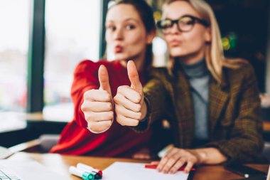 Kameraya bakarak iki başarılı kız öğrenci wich, üye seçici odak seviyor. Arka plan birlikte dizüstü bilgisayarda Üniversitesi'nde çalışan yukarı başparmak gösterilen mutlu arkadaşlarım ile bulanık