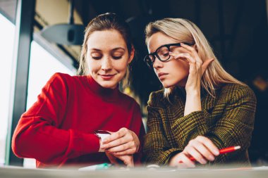 Eğitim zaman alan coworking içinde düzenlemek için düşünceli öğrenciler modern smartwatch göstermek vasıl arıyorum. Hippi kız kafe iç dostu toplantı sırasında kol saati kontrol