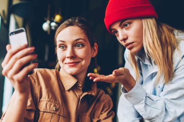 Hipster blogcular video web sitesi wich smartphone aygıt üzerinde online bağlı 4 g için izlerken üzerinde tartışırken merak internet kafede oturuyor. Şok öğrenciler canlı akışı mobil iletişim