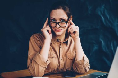 Yarım uzunluk portre gözlük 4 g kablosuz ile modern dizüstü bilgisayar başında otururken kameraya gülümseyen sağlamak gözleri koruma için müreffeh hipster öğrencinin şık coworking internet