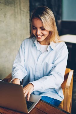 Kablosuz internet kullanarak Web sitesinde online arkadaşıyla sohbet mutlu sarışın kadın serbest meslek modern netbook için bağlı. Uzaktan coworking dizüstü bilgisayarda çalışan başarılı grafik tasarımcı