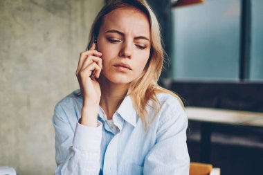 Ciddi hipster öğrenci kafede otururken smartphone aygıtında için işlecini çağırmak. Dalgın genç kadın dikkatle dinleme sesli mesaj kafede oturan telefonu operatörünüzden