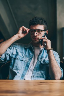 Görme düzeltmesi için gözlüklü düşünceli hippi dengeyi kontrol etmek için operatöre telefon ediyor, ciddi bir adam kablosuz internet kullanıyor ve arkadaşıyla iletişim kurmak için yeni mobil uygulama kullanıyor.