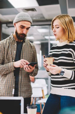 İki hipster öğrenci Smartphone'da yüklemek için kahve molası sırasında yeni uygulamaya tartışıyor. Hücresel operatör gelen bildirim hakkında konuşurken sakallı meslektaşım olan kadın