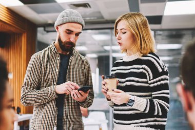 İki hipster öğrenci Smartphone'da yüklemek için kahve molası sırasında yeni uygulamaya tartışıyor. Hücresel operatör gelen bildirim hakkında konuşurken sakallı meslektaşım olan kadın