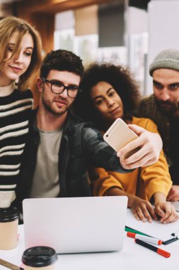 Genç takım yaratıcı çok kültürlü öğrenci Üniversitesi'nde mola sırasında modern smartphone ön kamera üzerinde fotoğraf yapma. Cep telefonu dizüstü bilgisayarlar oturan selfies alarak rahat giyinmiş hipster çocuklar