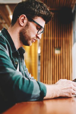 Telefon app denetleme çalışma işlemini Planlama şık kıyafeti giymiş yakışıklı yaratıcı erkek tasarımcısının resim kırpılmış. Sakallı ciddi adam cep üzerinde yararlı bir araç kullanarak müşteri ile sohbet