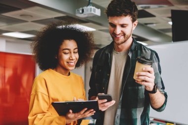 Smartphone uygulama kullanarak yeni iş proje planı oluştururken gülüyor duygusal hipster adamlardan resim kırpılmış. Neşeli erkek ve kadın çalışanların birlikte ortak çalışma sırasında eğlenmek