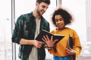 İyi görünümlü kırpılmış görüntü gülümseyen adam ve büyüleyici pozitif kadın birlikte beyin fırtınası sırasında eğlenmek sakallı. Başarılı erkek ve dişi pencere karşı ayakta birbirleri ile iletişim