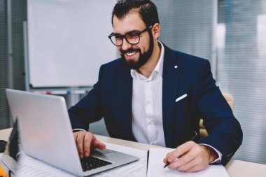 Kablosuz 4 g internet yazarken notlar için aşağı üretken çalışma ofisinde oturan müreffeh sakallı girişimci iş webinar online web sitesinde dizüstü bilgisayar izlerken bağlı