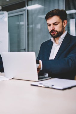 Resmi giyinmiş bir grup yetenekli genç mimar dizüstü bilgisayarda uygulama kullanarak sunum yapıyor. Profesyonel çalışanlar kapalı alanlarda modern teknolojiyi kullanarak birlikte çalışıyorlar.