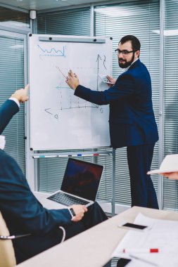 Flip grafik yanında duran ve ortakları için grafik çizim gözlük akıllı executive CEO'su sakallı. Erkek ve kadın yetenekli tüccarlar office işbirliği sırasında yeni fikirler tartışıyor