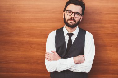 Reklam metinleri için fotokopi alanının yakınında poz veren beyaz tenli hippi adam. Promosyon arka planının yanında duran ve boş zamanlarında kameraya bakan kendine güvenen gözlüklü adam.