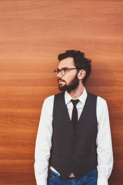 Gözlüklü, gözlüklü, gözlüklü bir hippi. Tanıtım arkaplanının yanında duruyor ve dışarıda arkadaşını beklerken başka tarafa bakıyor. Reklam için fotokopi alanının yanında modaya uygun giyinmiş genç bir adam.