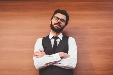 Şık giyinmiş başarılı bir erkek öğrenci ve modaya uygun gözlüklerle dışarıda kameraya bakıyor. Yüzünde şirin bir gülümseme olan genç, pozitif hipster sokak arkadaşını bekliyor.