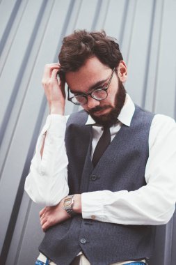 Moda kıyafetleri içinde düşünceli bir hippi, reklam metni için fotokopi alanının yakınında kafa yoruyor, düşünceli bir adam reklam alanının yakınında vakit geçiriyor, dışarıda arkadaşını beklerken düşünüyor.