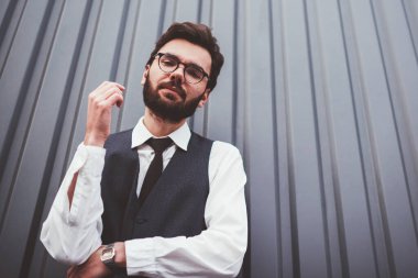 Beyaz tenli yakışıklı adamın portresi. Gri promosyon arka planının yakınındaki kameraya bakıyor. Gözlüklü genç bir öğrenci.