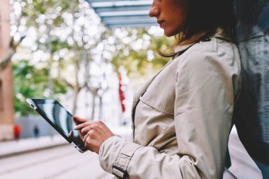 Posta kontrol ve bildirim istimal özgür 4 g dokunmatik yüzey üzerinde okuma trendy ceket genç kadın yan görünüm kırpılmış Internet. Dalgın kadın blogger profil sayfası tramvay durağı tablet ayakta güncelleştiriliyor