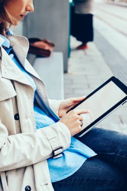 Tramvay durağı üzerinde oturan 4 g internet bağlantısı ile modern tablet medya dosyalarını seçerek şık genç kadın yan görünüm kırpılmış. Beyaz kadın dijital dokunmatik yüzey boş ekranda metin yazma