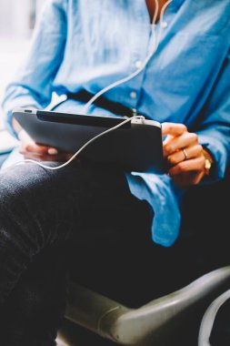 Dokunmatik yüzey üzerinde sosyal ağlar sohbet ve kulaklık bağlı tramvayda oturan aygıt radyo dinleme kadın yolcu görünümünü kırpılmış. 4 g kullanarak dijital tablet holding kadının eller Internet