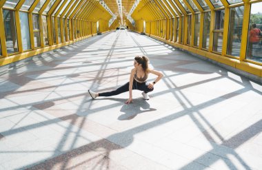 Güneş banyosu yapan sarı yaya köprüsünde uzanan kararlı, beyaz kadın esnekliğine ve gücüne odaklanmış, açık hava spor programının bir parçası..