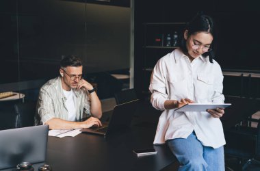 Milenyum Asyalı kadın optik gözlüklerle web içeriğini modern dokunmatik ped üzerinde tarıyor, dijital tablette dijital mesajlaşma için 4G 'ye bağlanan gözlüklerde grafik tasarımcısı