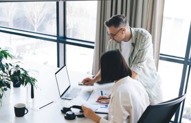 Dizüstü bilgisayarı kopyalamak için kullanan yetenekli erkek ve kadın çalışanlar, masaüstündeki işbirliği brifinginde metin reklamları, iş dünyası için boş ekranlı netbook teknolojisi içindir.