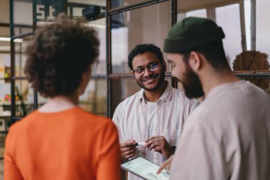 Modern işyerinde projeyi tartışırken tablet üzerinde gülümseyen ve bilgi paylaşan günlük kıyafetli bir grup iş arkadaşı