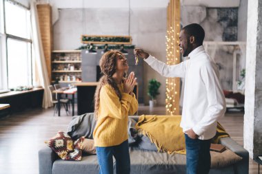 Beyaz gömlekli adam sarı kazaklı kadına anahtarlarını sunuyor. İkisi de geniş, modern bir dairede neşe saçıyor. Gayrimenkul hayalleri gerçek oluyor. Hayali, aydınlık, modern çatı katında birkaç yeni ev alımı.