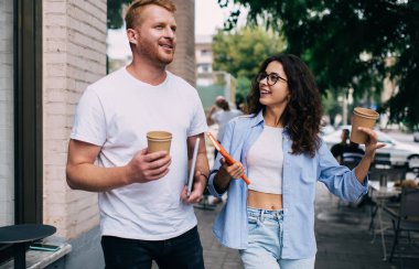 Görme düzeltmesi için optik gözlüklü gülümseyen kadın iş görüşlerini portatif dizüstü bilgisayar taşıyan erkek meslektaşla tartışıyor, genç bir erkek ve kadın kahve alıp konuşmaya gidiyor.