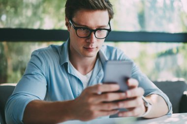Dalgın genç gözlük vizyon düzeltme online sosyal ağlar kahvehane iç oturan ücretsiz 4 g internet bağlantısı kullanarak modern smartphone aygıt üzerinde arkadaşları ile sohbet için