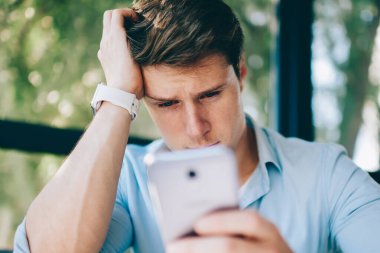 Kötü haber modern smartphone ile SMS mesajý okurken ağlıyor depresif genç adam. Video blog 4 g internet bağlantısı kullanarak dijital telefon üzerinde izlerken endişeli hipster öğrenci