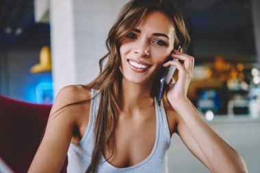 Notlar ve smartphone aygıt üzerinde arama yaparken kameraya gülümseyen neşeli hippi kız portresi. Kafe iç cep telefon konuşma sırasında gülüyor olumlu genç kadın