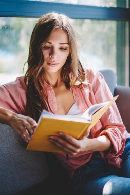 Dalgın genç kadın eğlence zaman rahat kanepede kafede zevk favori kitap okuma. Edebiyat bestseller kafe iç dinlenme zevk akıllı hippi kız konsantre