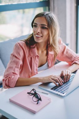 Neşeli kadın freelancer gülüyor ve internet sitelerinde arama bilgi modern dizüstü cihazda klavye tarafından bakarım. Uzaktan çalışma dijital netbook olumlu genç kadın