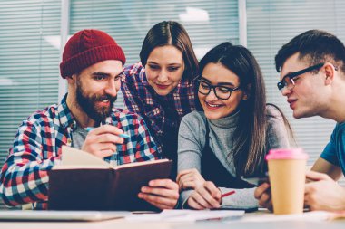 Olumlu bir grup genç insan ofiste toplantı sırasında işbirliği planı geliştirme ortak proje üzerinde tartışırken rahat kıyafet giymiş. Erkek lideri tasarım eskiz defter meslektaşları gösterilen