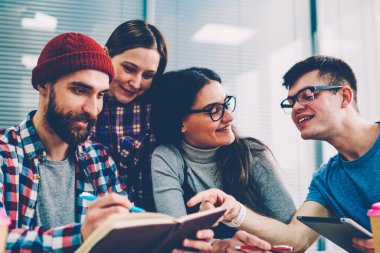 Takım başarılı uzmanları çalışma işlemi ofiste tabloda toplantı oturma planını tartışırken gülüyor. Gençlerin grup ortak proje üzerinde işbirliği yaratıcı