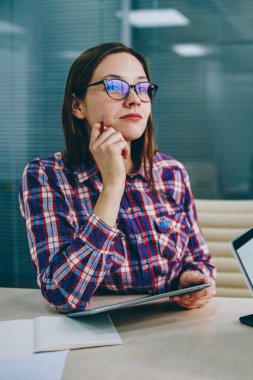 Rüya gibi genç kadın çekici rahat kıyafet düşünme plan geliştirme kendi iş başlangıç Dokunmatik ped cihaz ile masada oturan giymiş. Yaratıcı fikirler üzerinde durulması düşünceli kadın blogger