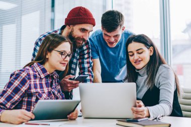 Yaratıcı grafik tasarımcılar ekibi giyinik rahat kıyafet modern dizüstü bilgisayarda kablosuz 4 g kullanarak geliştirme web sitesinde işbirliği içinde Office Internet. Komik öğretici izlerken öğrenci grubu