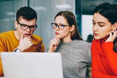 Dalgın yetenekli öğrencileri ile birlikte izlerken ciddi yüzler webinar Web sitesinde seminer için hazırlama alanı coworking içinde kablosuz internet bağlantısını kullanarak modern dizüstü bilgisayar eğitim