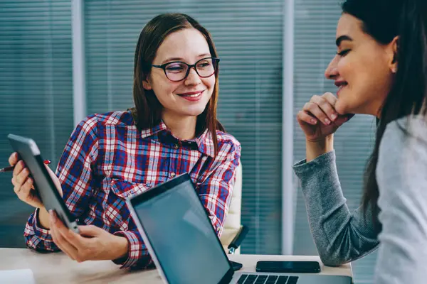 Ortak görev üzerinde işbirliği sırasında pozitif meslektaşları komik video modern touch üzerinde tartışırken yastık. Dizüstü bilgisayar ofiste oturan öğretici arkadaş gösterilen Eyewear neşeli genç kadın