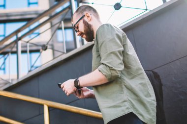Merdivenlerden ve 4 g kullanarak modern smartphone aygıt üzerinde gelen bildirim okuma genç adam rahat giyinmiş Internet. Sosyal ağlar üzerinde cep kentsel ortamda sohbet hipster blogger