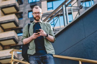 Modern smartphone aygıtında ücretsiz 4 g kullanarak online sohbet mesajlaşma dalgın genç adam Internet kentsel merdiven merdiven iniyor. Hipster blogger üstünde hareket eden telefon bildirim okuma